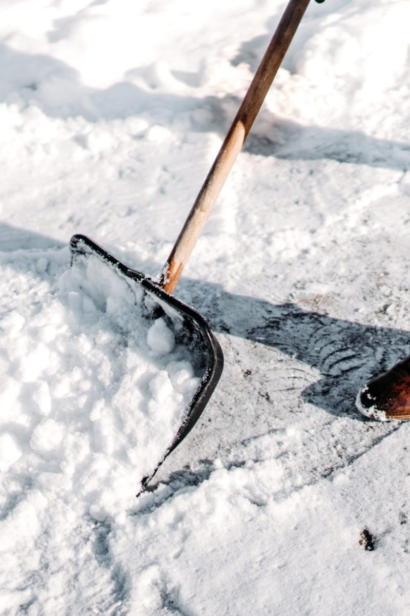Man cleaning snow from house alley. Details of male using snow shovel