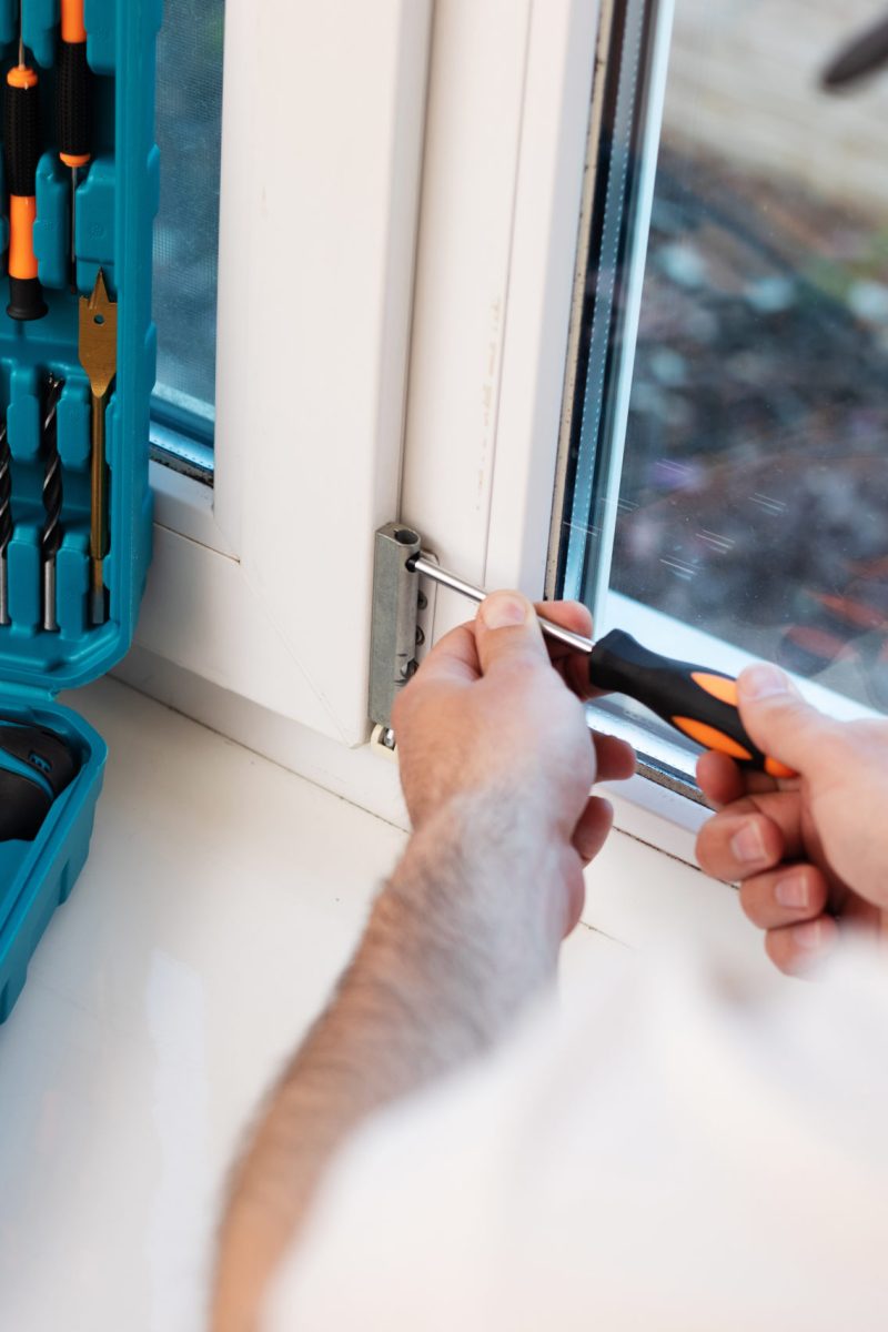 Young professional worker man in uniform suit is installing window with help of tools